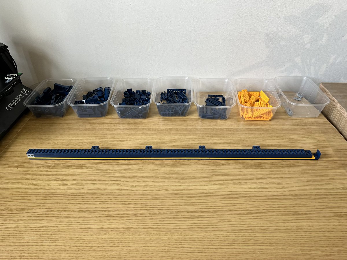 A long straight structure made of dark blue and yellow lego. It stretches almost across the entire desk.