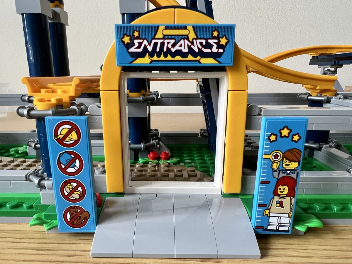 The entrance to a lego roller coaster. It’s a yellow arch with a sign saying “entrance”, a poster that bans hats, balloons, hot dogs, and squirrels, and another sign with a measuring scale showing how tall you have to be to ride.