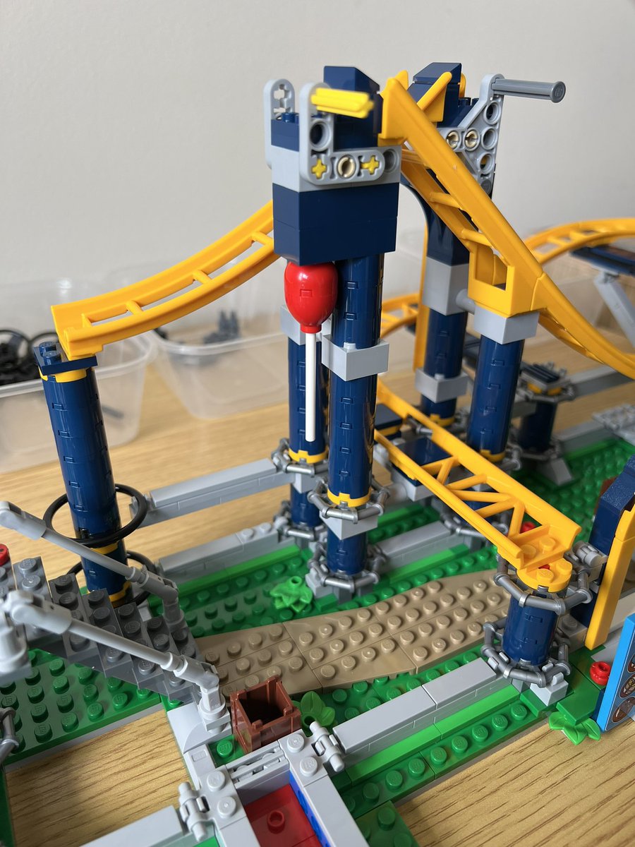 A lego roller coaster track with a red balloon under one of the track supports