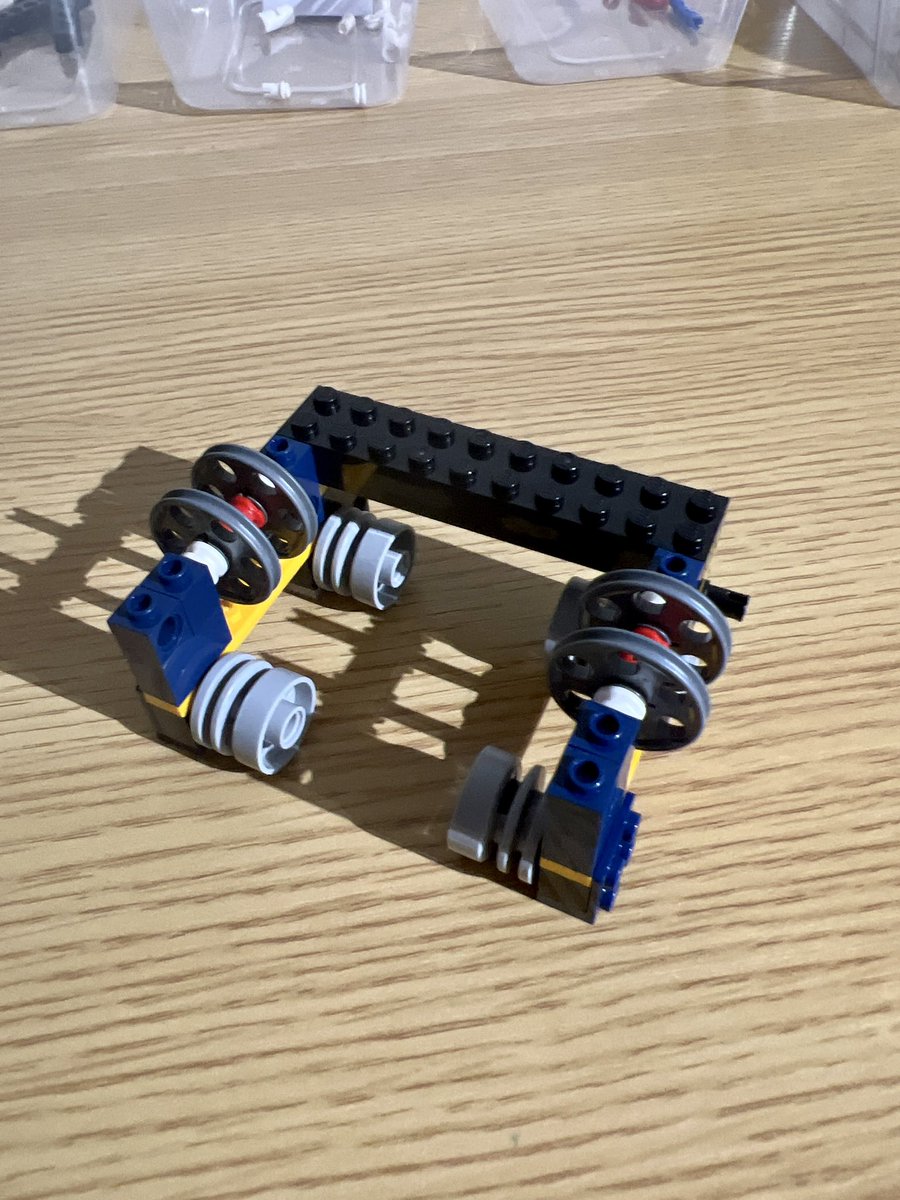 A small square lego structure with four wheels on the bottom and two sets of thinner wheels on the top.