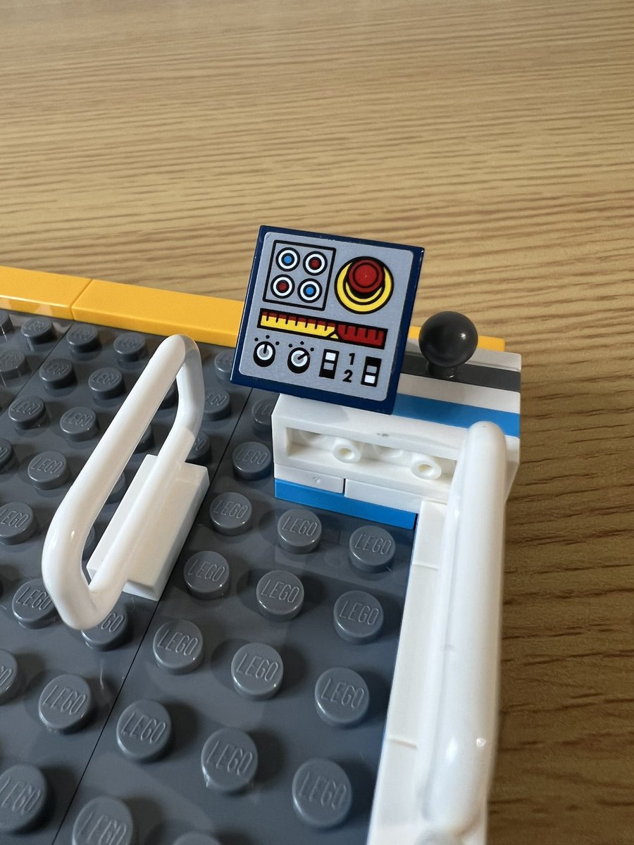 A closeup of the control panel for a lego roller coaster. It has various lights, switches, and dials, and a big red button.