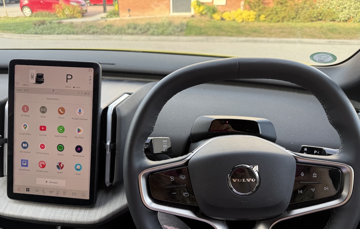 The interior of the car, which has a large touchscreen to the left of the steering wheel, displaying a homescreen of app icons.